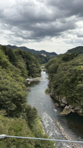 吊橋からの景色。曇天の下を、大きな川が流れています。