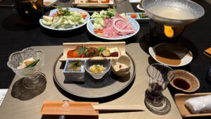 左から、先付の寄せ湯葉豆腐、前菜いろいろ、食前酒、しゃぶしゃぶのお出汁とごまポン酢。奥にしゃぶしゃぶのお肉と野菜が乗ったお皿が見えます。