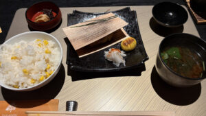 左から、もろこしご飯、香物、焼かれたなにか、赤だしのお味噌汁。