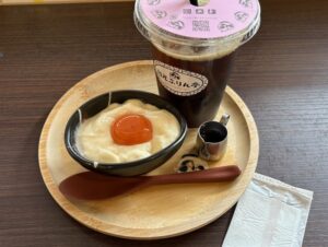 木のお盆の上に、白いプルプルの上に卵黄がのったものと、コーヒーと、カラメルソース。