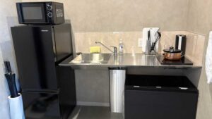 キッチン。電子レンジと冷蔵庫もあり、IHヒーターの上には小さめのフライパンとお鍋も。